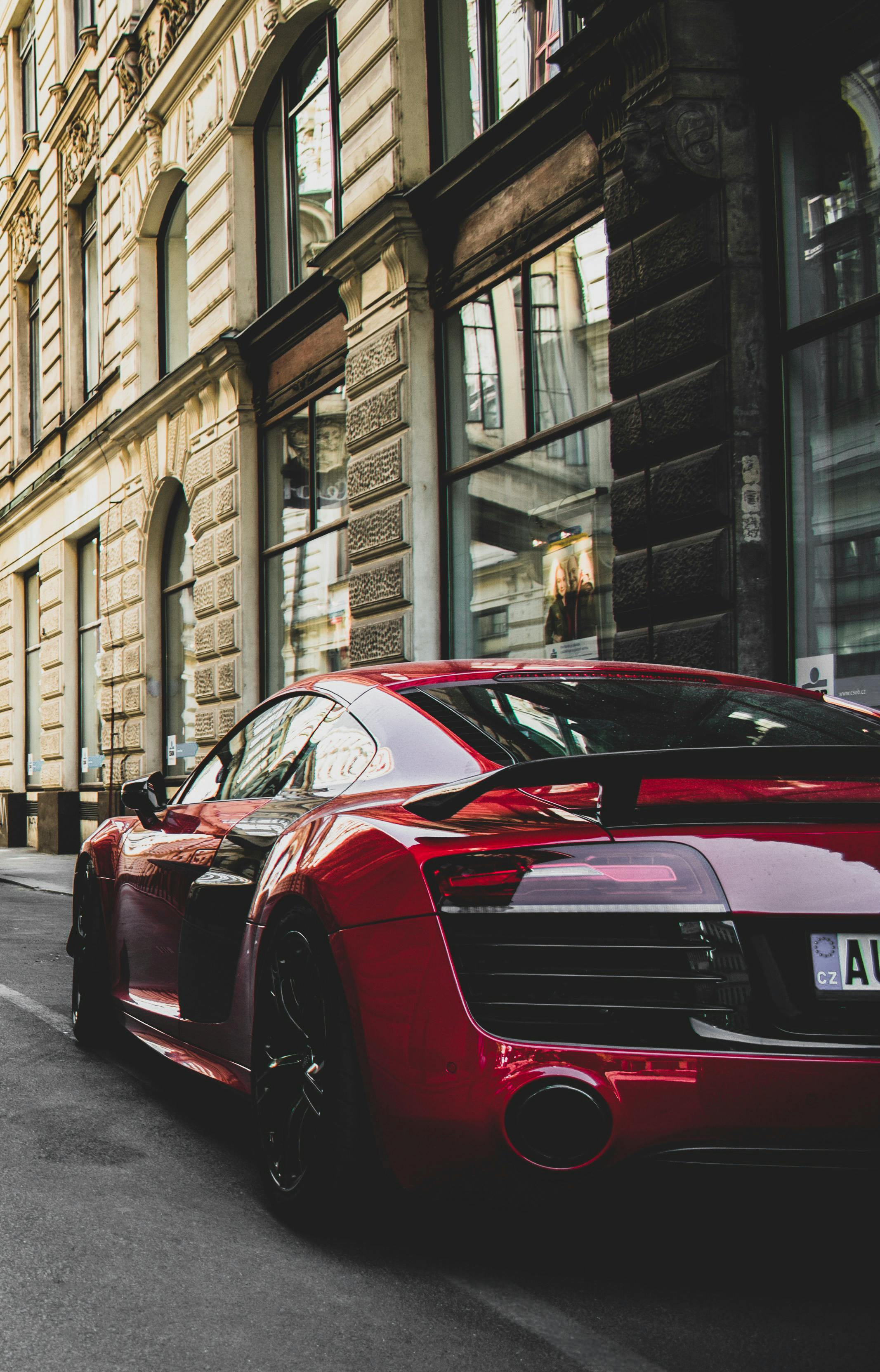 Red sports car parked on a city street with buildings in the background