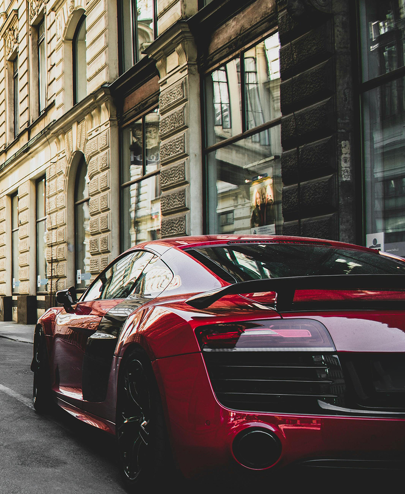 Red sports car parked on a city street with buildings in the background
